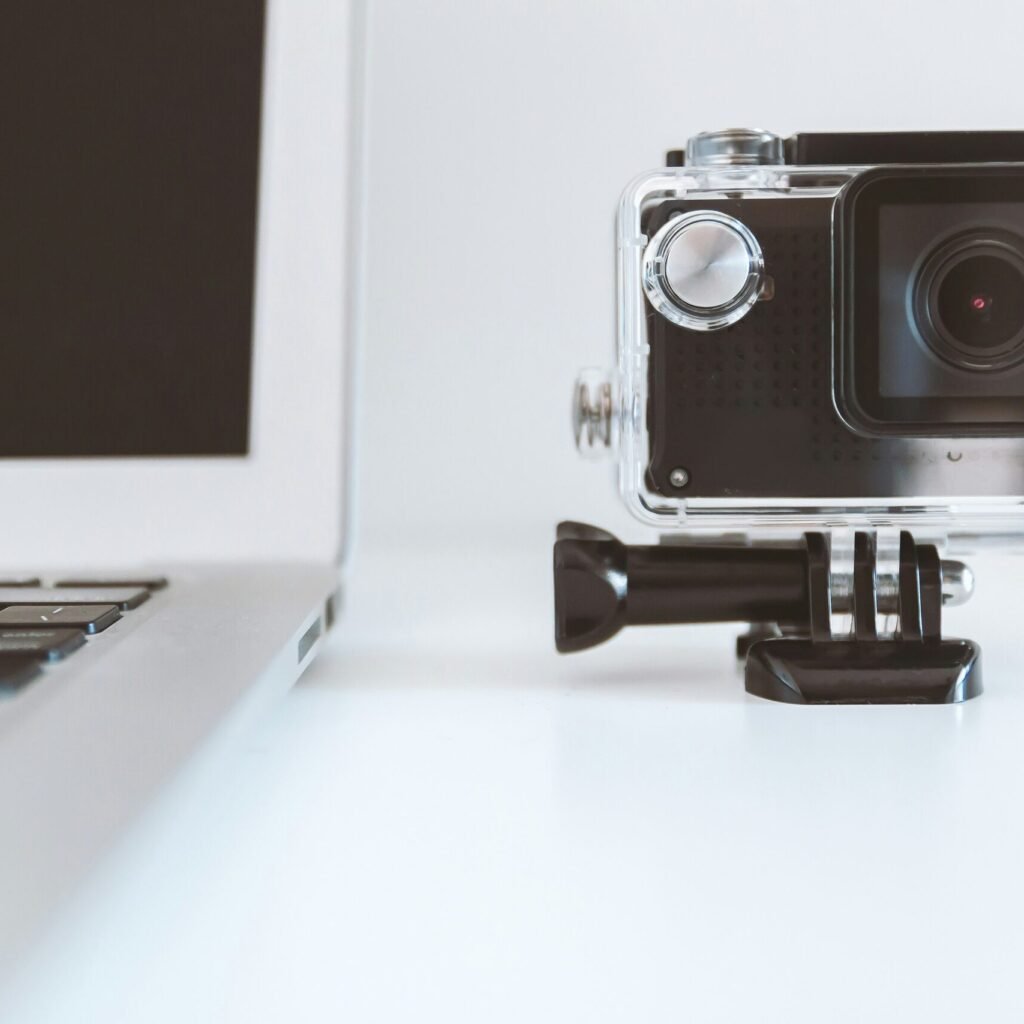 black action camera beside white laptop